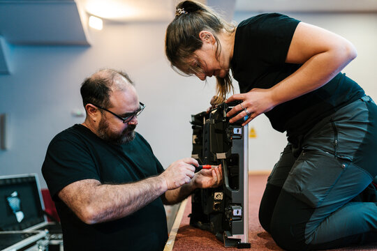 Professional mechanics fixing LED display while working in auditorium