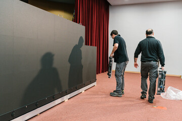 Men engineers carrying LED display panels on stage