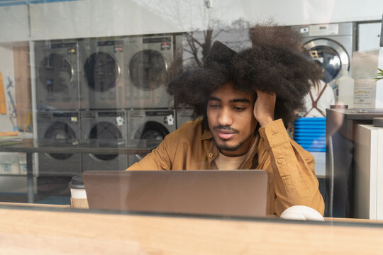 Contemplative Man with Laptop at Laundromat