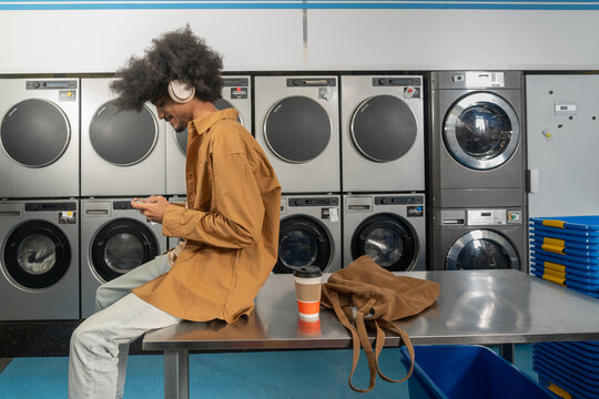 Man Texting with Coffee at Laundromat