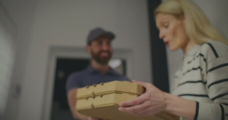Pizza delivery man entering apartment of beautiful Caucasian woman. Female taking her order. Thanking handsome courier for delivering her food so fast. Going to enjoy hot delicious food.
