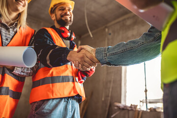Contractor.Construction worker team hands shaking after plan project contract  at construction...