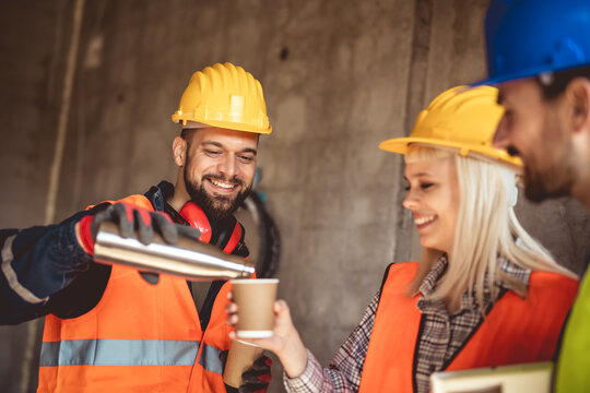 Three constructions workers having a coffee break at construction site