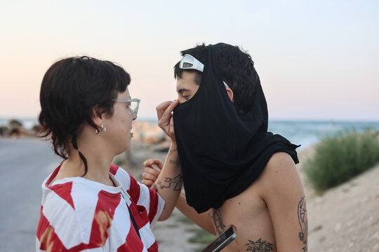 Z Generation couple help one another by the seaside