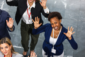 Multiracial business people standing excited with their hands up. View from above