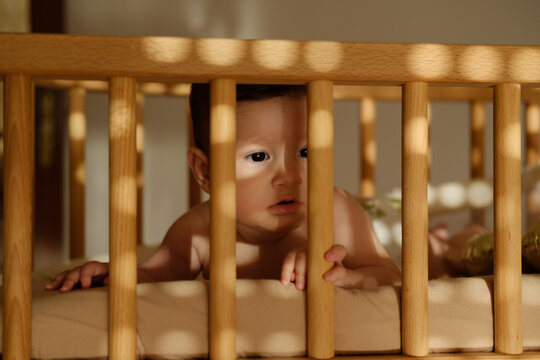 Baby in a wooden cot at home