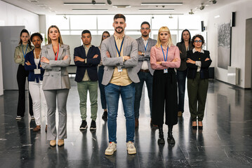 Fototapeta premium Portrait of young CEO businessman standing with his hands crossed in front of his colleagues.