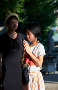 Asian mother and daughter praying in Japanese temple