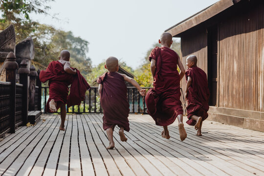 Monks playfully running on wooden deck