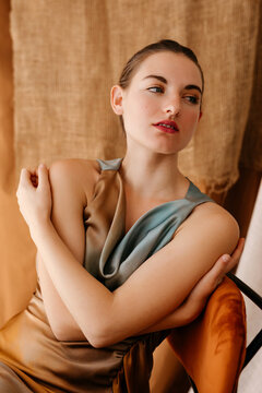 Stylish model embracing herself while sitting on chair