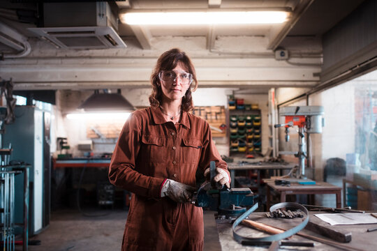 Female mechanic looking at camera at metal workshop