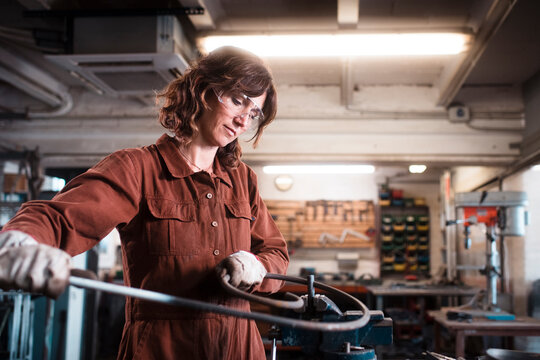Metal sculptor shaping iron piece at workshop
