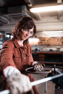 Female worker shaping iron piece at workshop