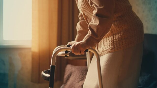 Sad elderly woman moving with walking frame at home, loneliness at old age