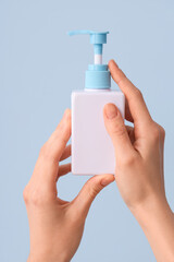 Female hands with bottle of natural cream against color background, closeup