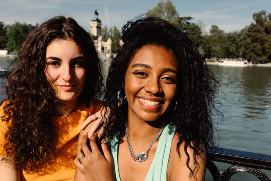 Two friends of different ethnicities happily posing in El Retiro park