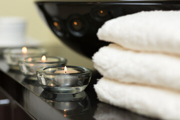 Burning candles and pile of towels