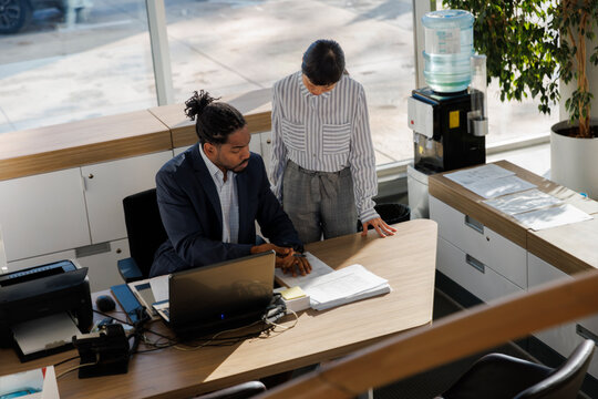 Manager discussing with colleague at desk