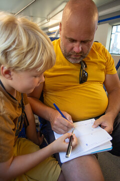 man with son playing some game on the notebook sitting on the train