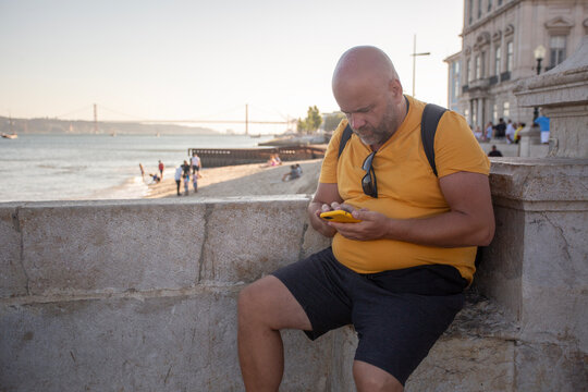man with phone sitting on the embankment