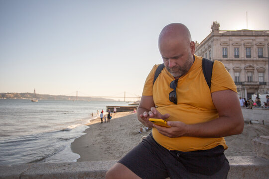 man with phone sitting on the embankment
