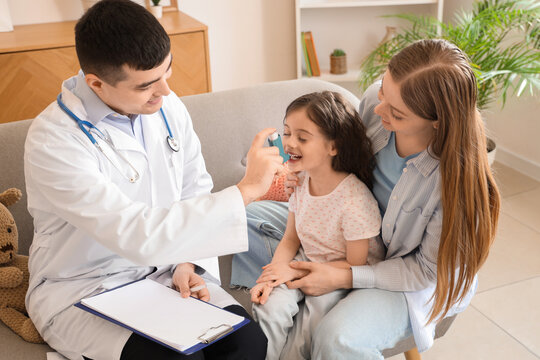 Little girl with her mother and doctor using inhaler at home