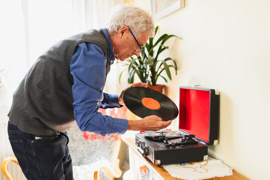 Senior man listening to vinyl disc at home