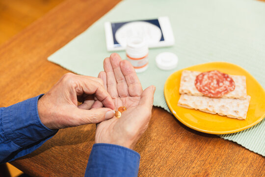 Hands of a senior man taking pills at home
