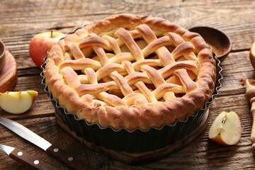 Tasty homemade apple pie with fruits and cutlery on wooden background