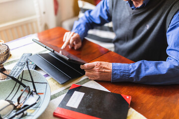 Senior man at home working on his digital tablet on the sofa