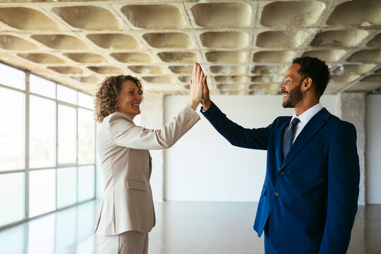 Real estate agents giving high five at empty loft