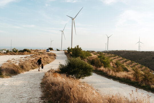 Hiker Approaching Wind Turbines at Dusk