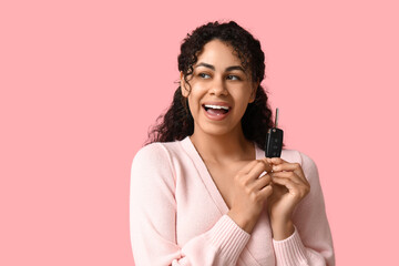 Beautiful young African-American woman with car key on pink background