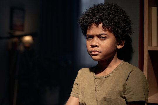 Cinematic closeup portrait of teen African American boy looking at camera with serious face expression copy space