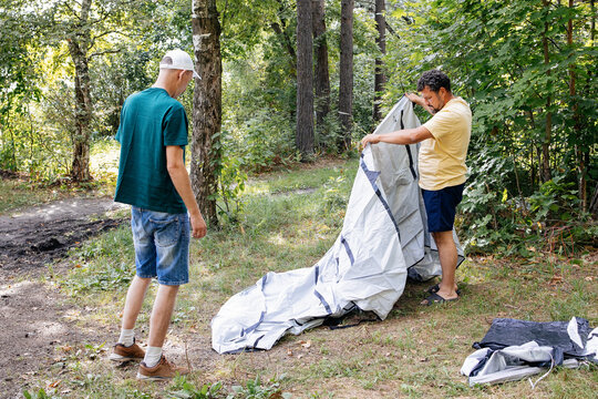 Two Men Setting Up Tent in Forest