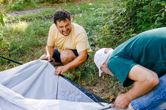 Two Men Setting Up Tent in Forest
