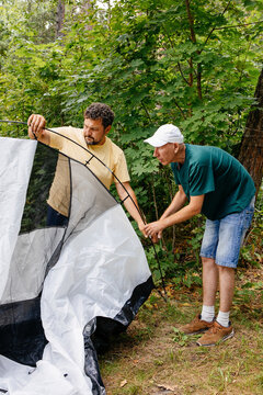 Two Men Setting Up Tent in Forest