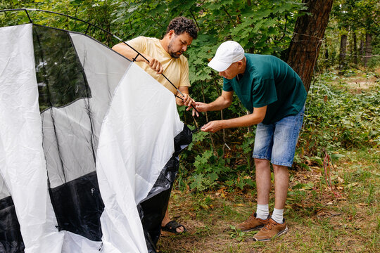 Two Men Setting Up Tent in Forest