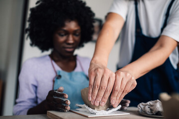 Close up of mentor demonstrating pottery to diverse attendee on class