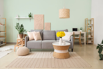 Beautiful interior of living room with grey sofa, coffee table and vase of narcissus flowers