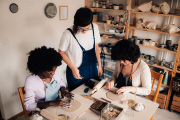Diverse creative students learning decorating clay techniques at workshop