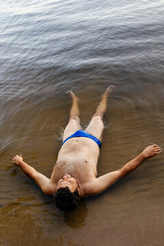A man lying on the shore in the water 