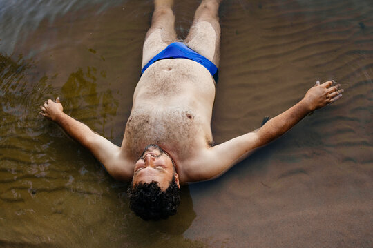 A man lying on the shore in the water 