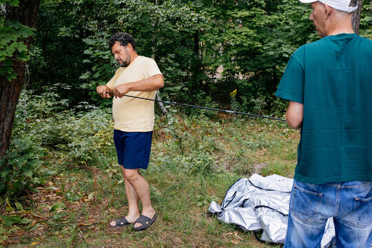 Two Men Setting Up Tent in Forest