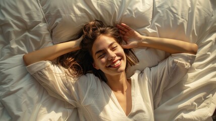 Naklejka premium Top view from above smiling young woman stretching, lying in comfortable bed after awakening, happy positive young female wearing pajama resting on soft pillows under warm blanket, enjoying morning.