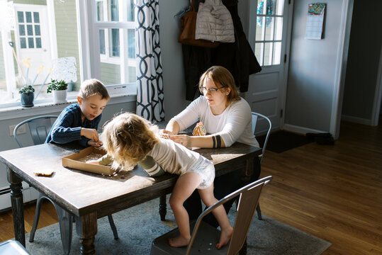 Family making gingerbread house crafting during holiday season at home