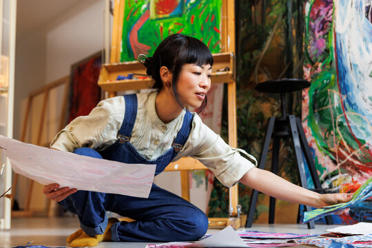 Smiling artist looking at painting at studio