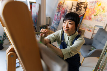 Smiling female artist painting in studio