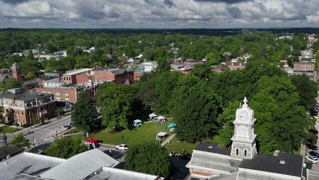 A slowly moving forward aerial establishing shot of the small Ohio town of Medina on a summer day. The clocktower of the Medina County Courthouse in the foreground.  	