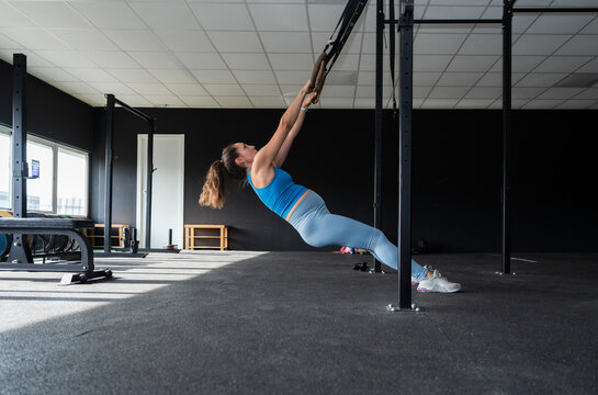 Pregnant woman performing trx suspension training in gym
